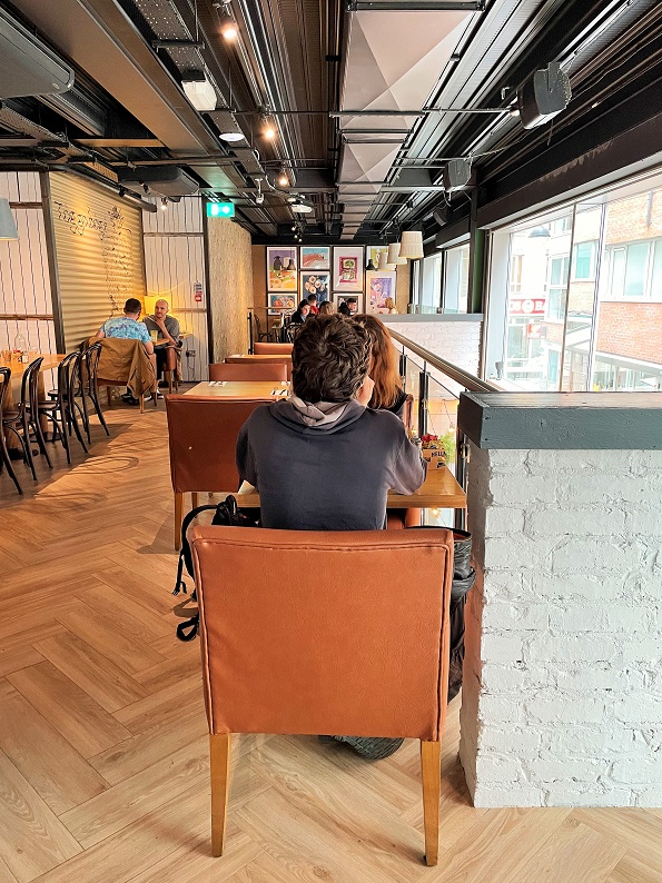 Photo showing the length of the comfortable upstairs lounge in Dublin city with customers sitting at the table in the foreground with their back to the camera, and other customers sitting at tables in the background